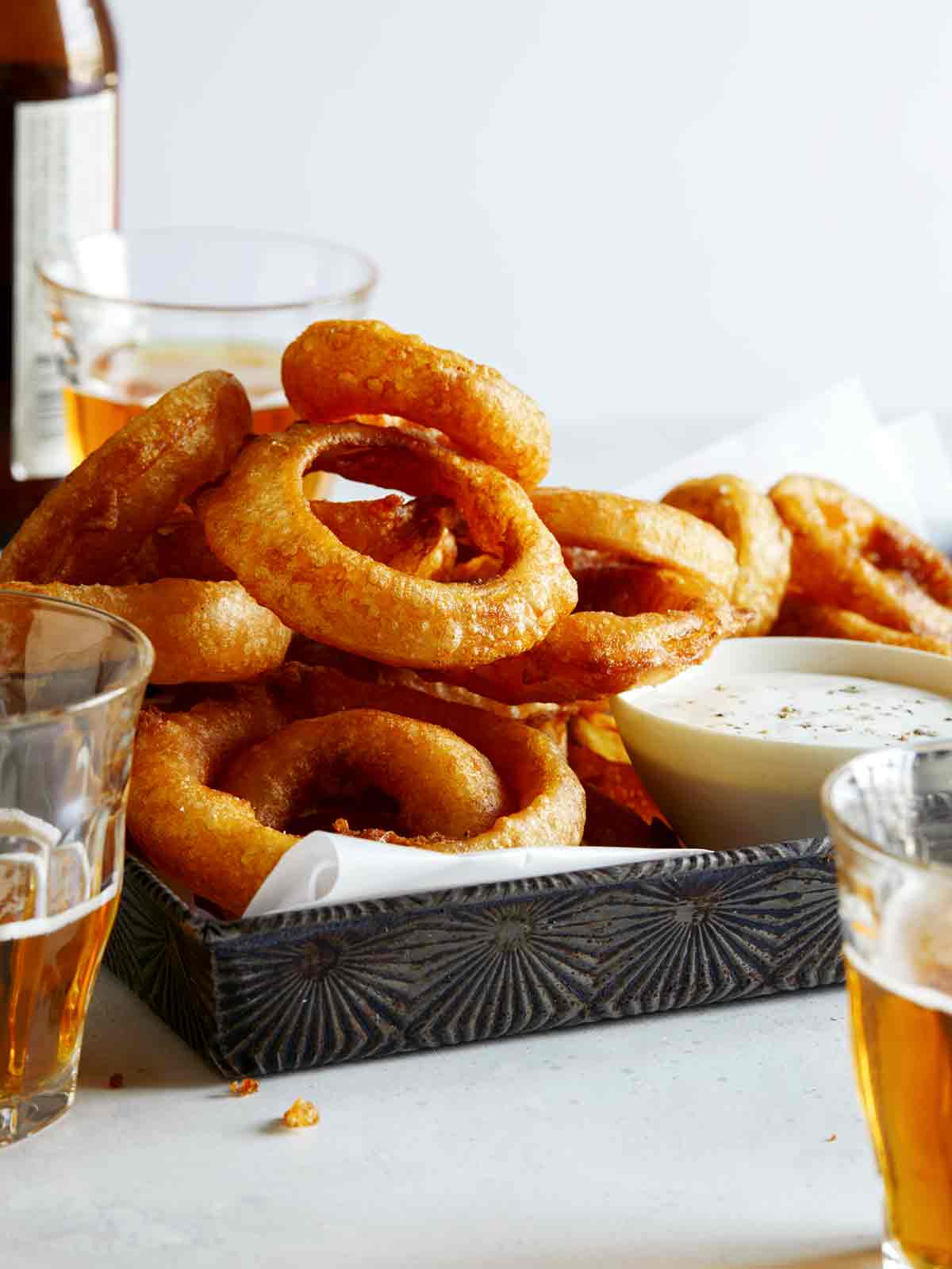 A tower of beer battered fried onion rings recipe with beer on the side.