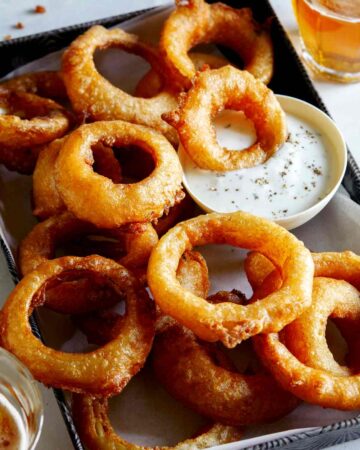 A serving of beer battered fried onion rings with ranch.