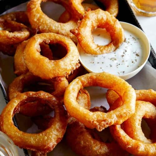 A serving of beer battered fried onion rings with ranch.