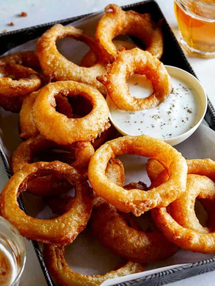 A serving of beer battered fried onion rings with ranch.