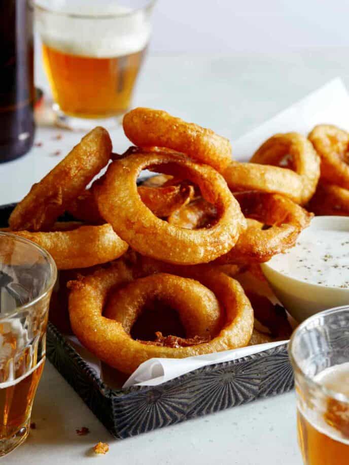 Beer battered fried onion rings with ranch dressing and beer on the side.