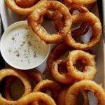 Close up on beer battered onion rings with ranch.