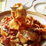 Bolognese sauce with pasta in a bowl with a fork picking some pasta up.