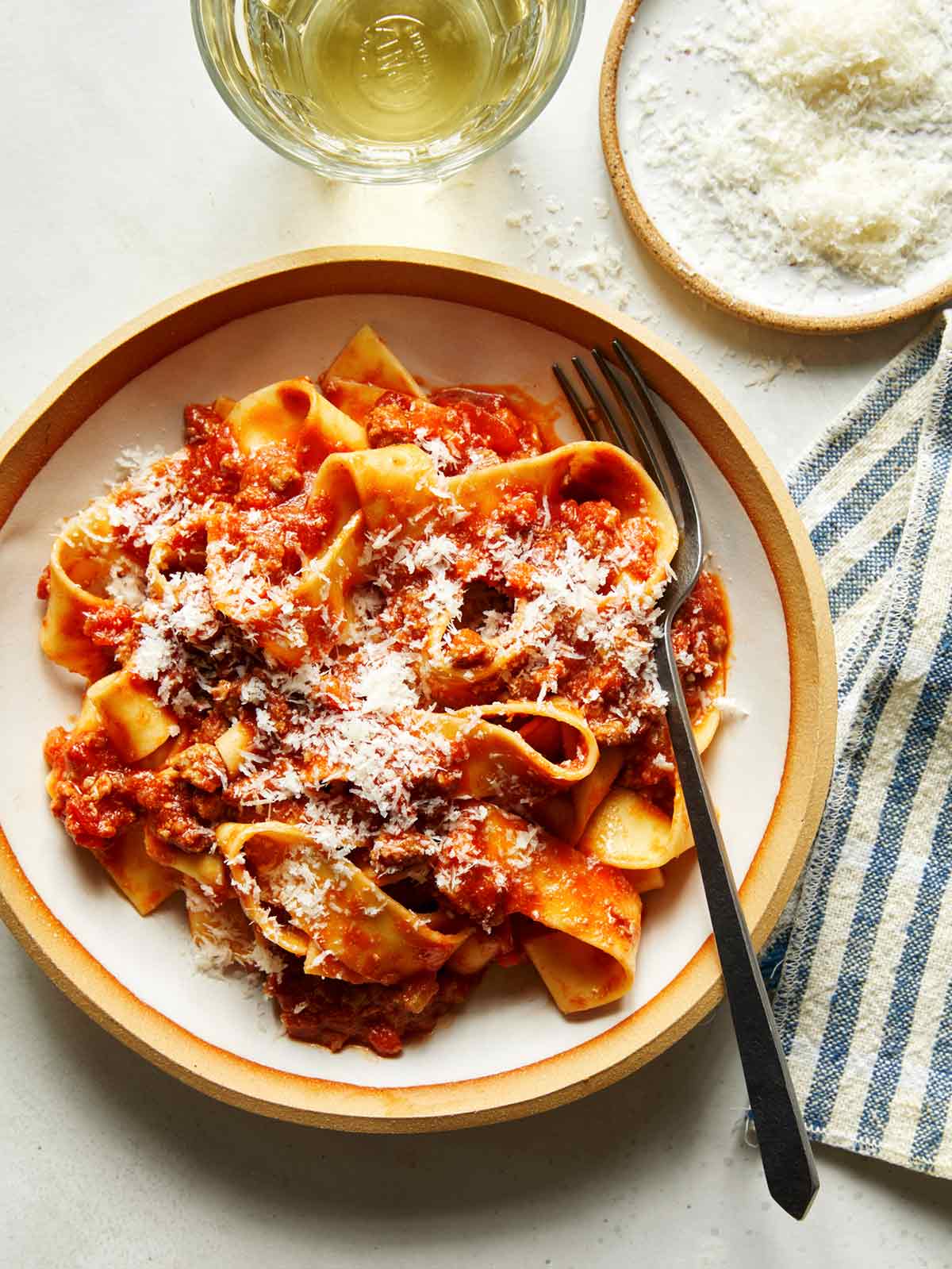 Bolognese sauce with pasta in a bowl and parmesan on the side.