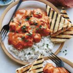 Butter chicken on a plate with rice.