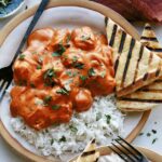 Butter chicken on a plate with rice.