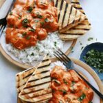 Butter chicken on a plate with rice.