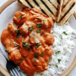 Butter chicken on a plate with rice.