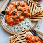 Butter chicken on a plate with rice.