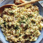 Creamy potato salad in a bowl with a beer on the side.