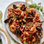 Frutti Di Mare recipe on a platter with basil leaves on the side.