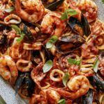 Frutti Di Mare recipe on a platter with basil leaves on the side.