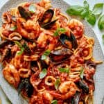 Frutti Di Mare recipe on a platter with basil leaves on the side.