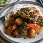 Galbi jjim served on a plate with rice and green onion.