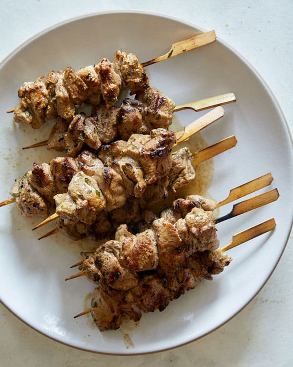 Grilled lamb kabobs on a plate resting.
