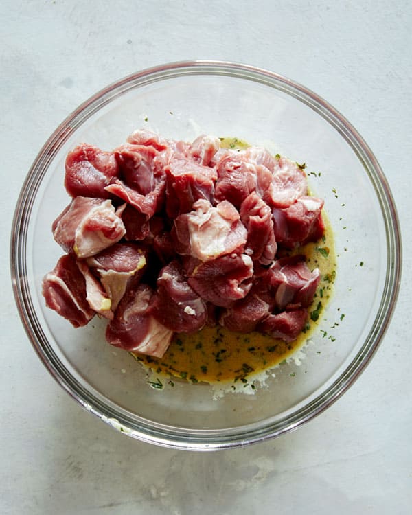 Lamb shoulder cubes in a bowl with marinade.