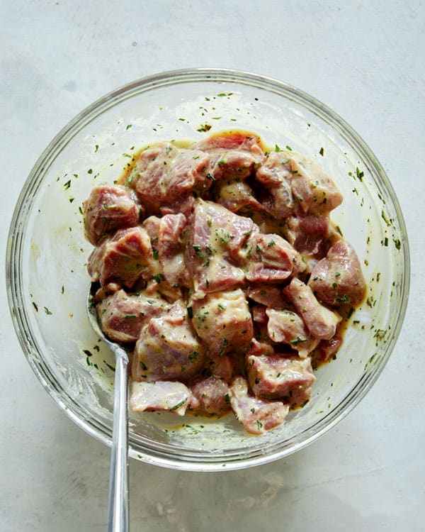 Lamb shoulder cubes marinating in a glass bowl. 