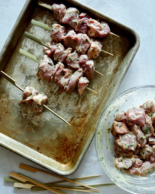 Skewering lamb kabobs to prepare them to grill.