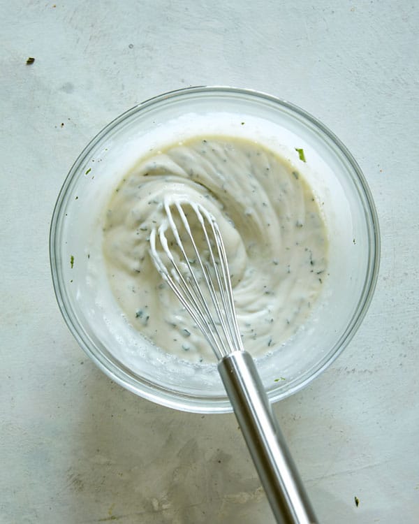 Mint yogurt sauce whisked together in a bowl.