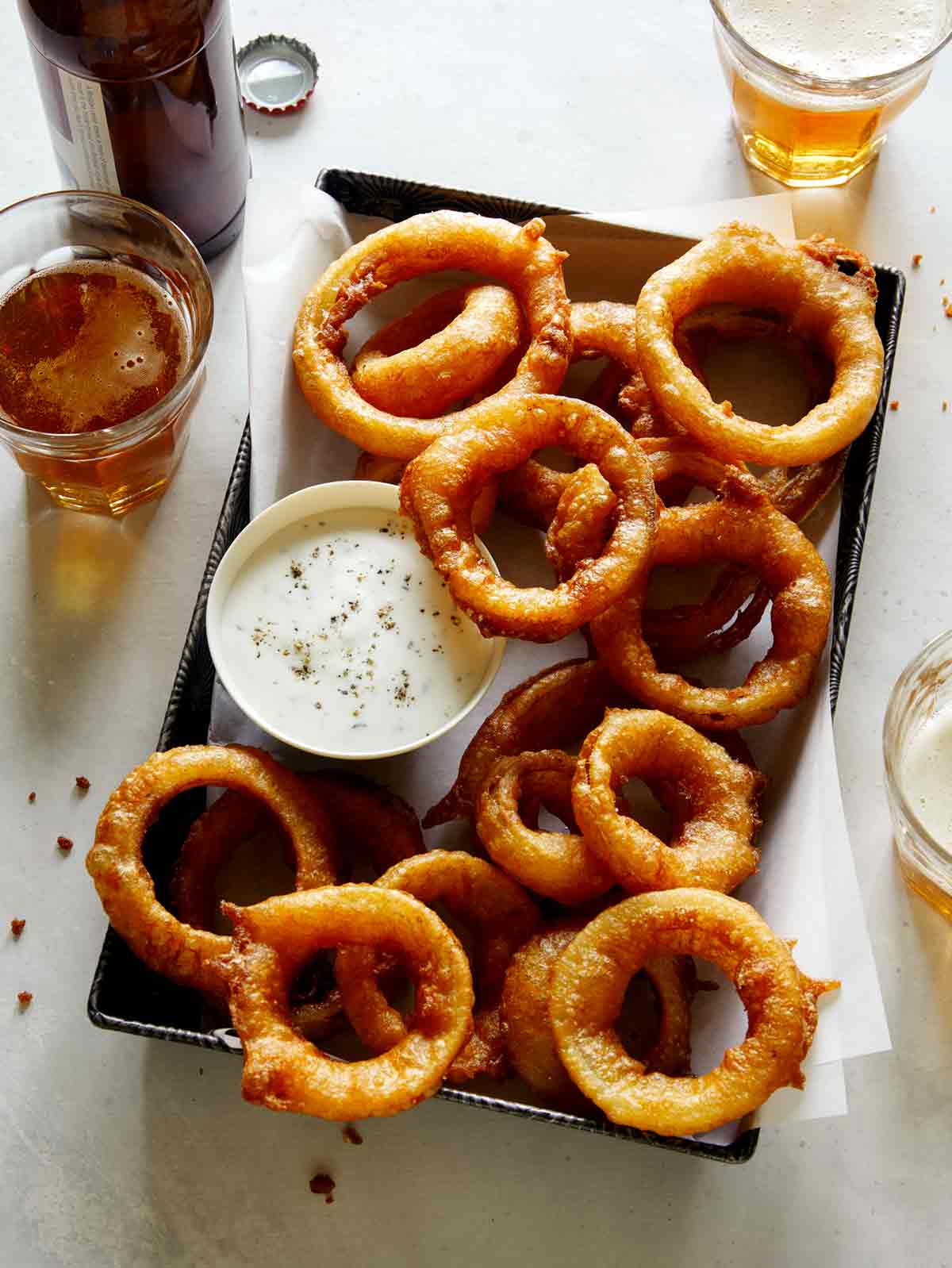 Beer battered fried onion rings with beer next to it.