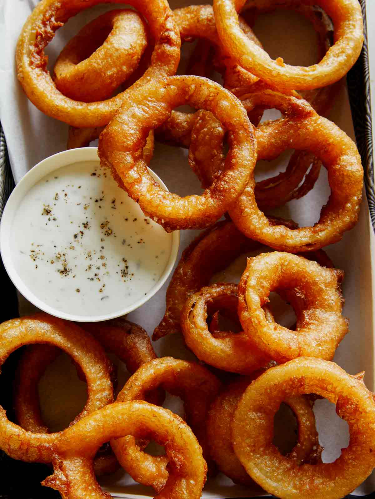 Close up on beer battered onion rings with ranch.