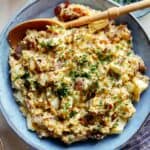 Creamy potato salad in a bowl with a beer on the side.