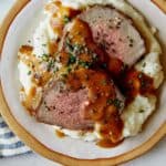 Roast beef plated with gravy and mashed potatoes.