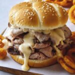 Roast beef sandwich with cheese on a cutting board.