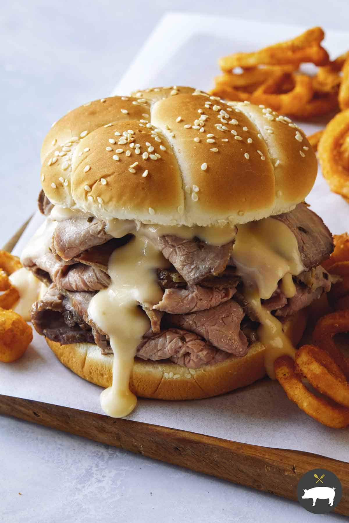 Roast beef sandwich with cheese on a cutting board.