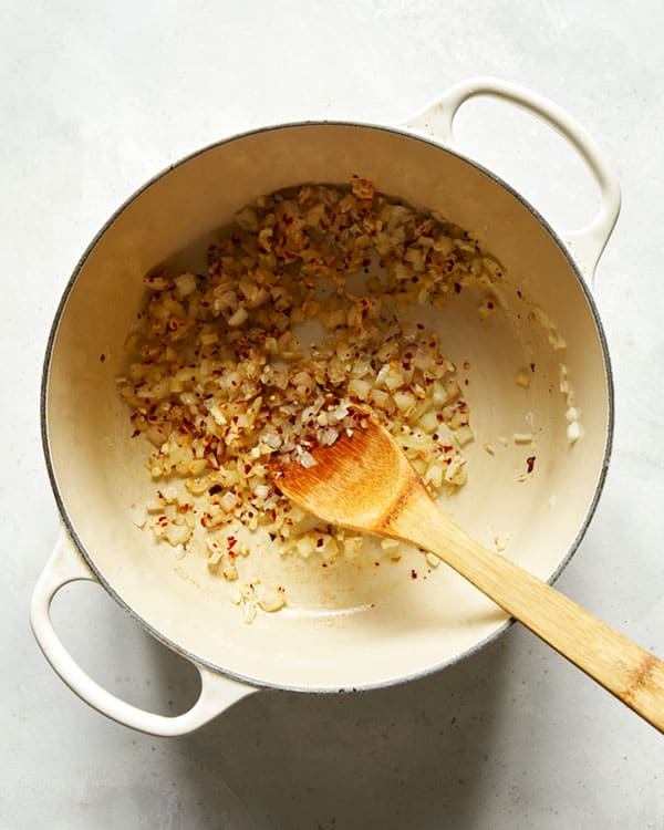 Onions and red pepper flakes cooking in a stock pot. 