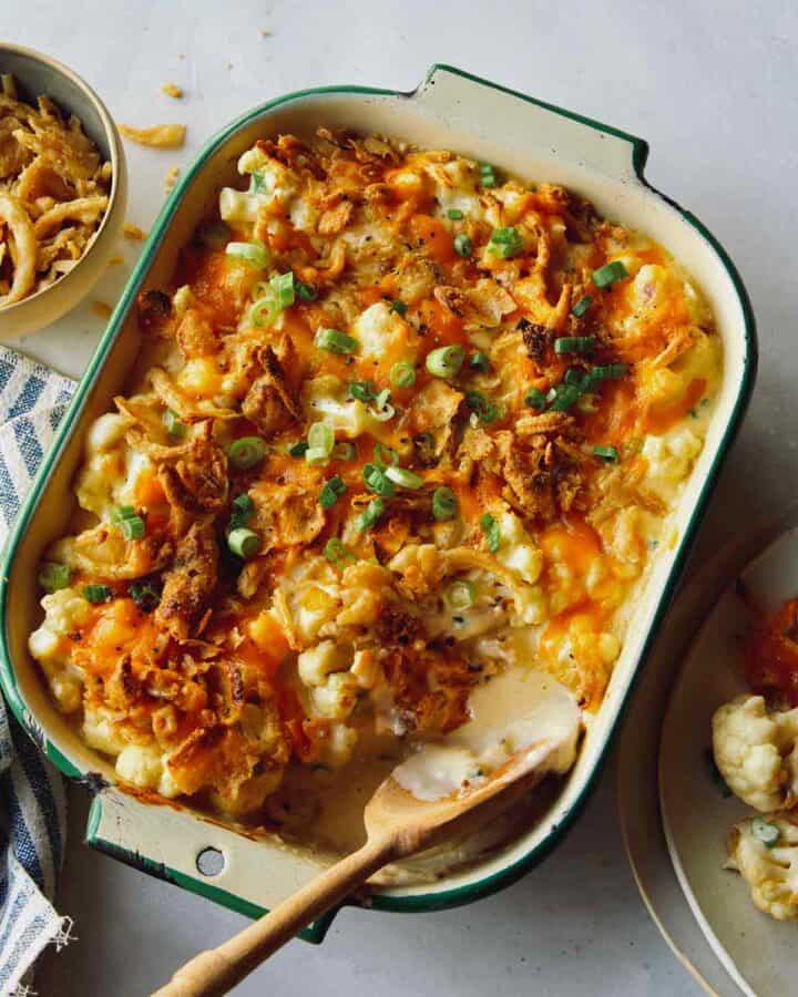 Creamy cauliflower bake recipe in a dish with some served onto a plate.