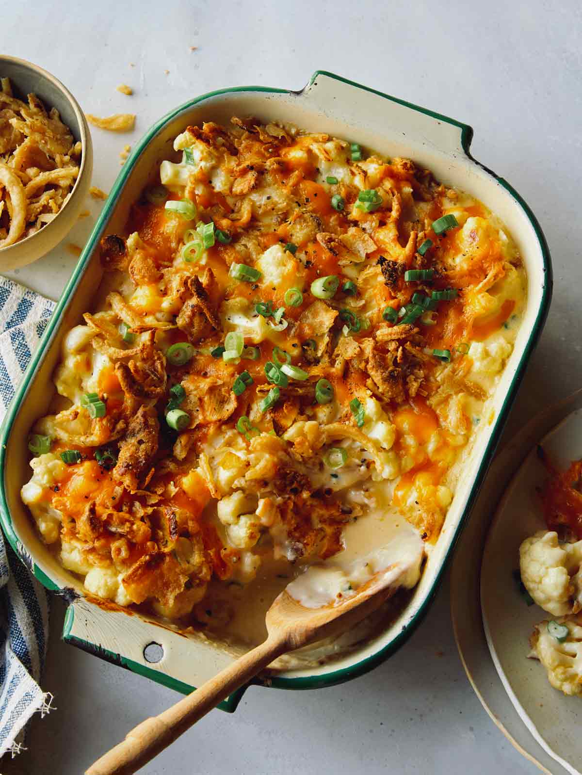 Creamy cauliflower bake recipe in a dish with some served onto a plate. 