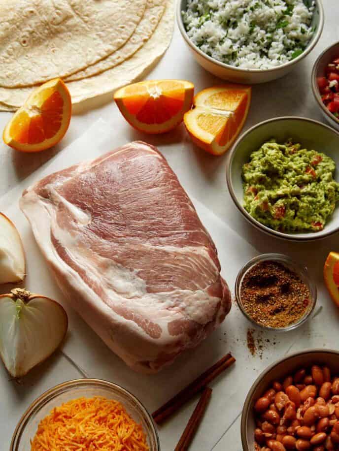 Pork carnitas ingredients all laid out on a kitchen counter. 