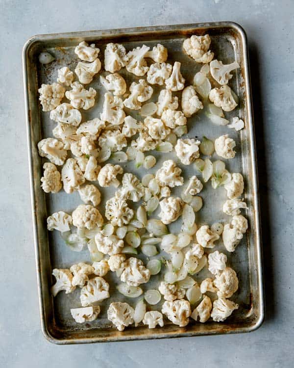 Cauliflower and pearled onions on a baking sheet. 