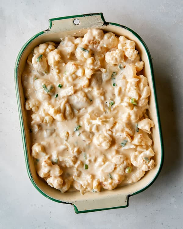 Creamy baked cauliflower in a baking dish ready to be baked. 