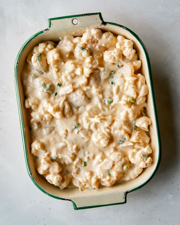 Creamy baked cauliflower in a baking dish ready to be baked.
