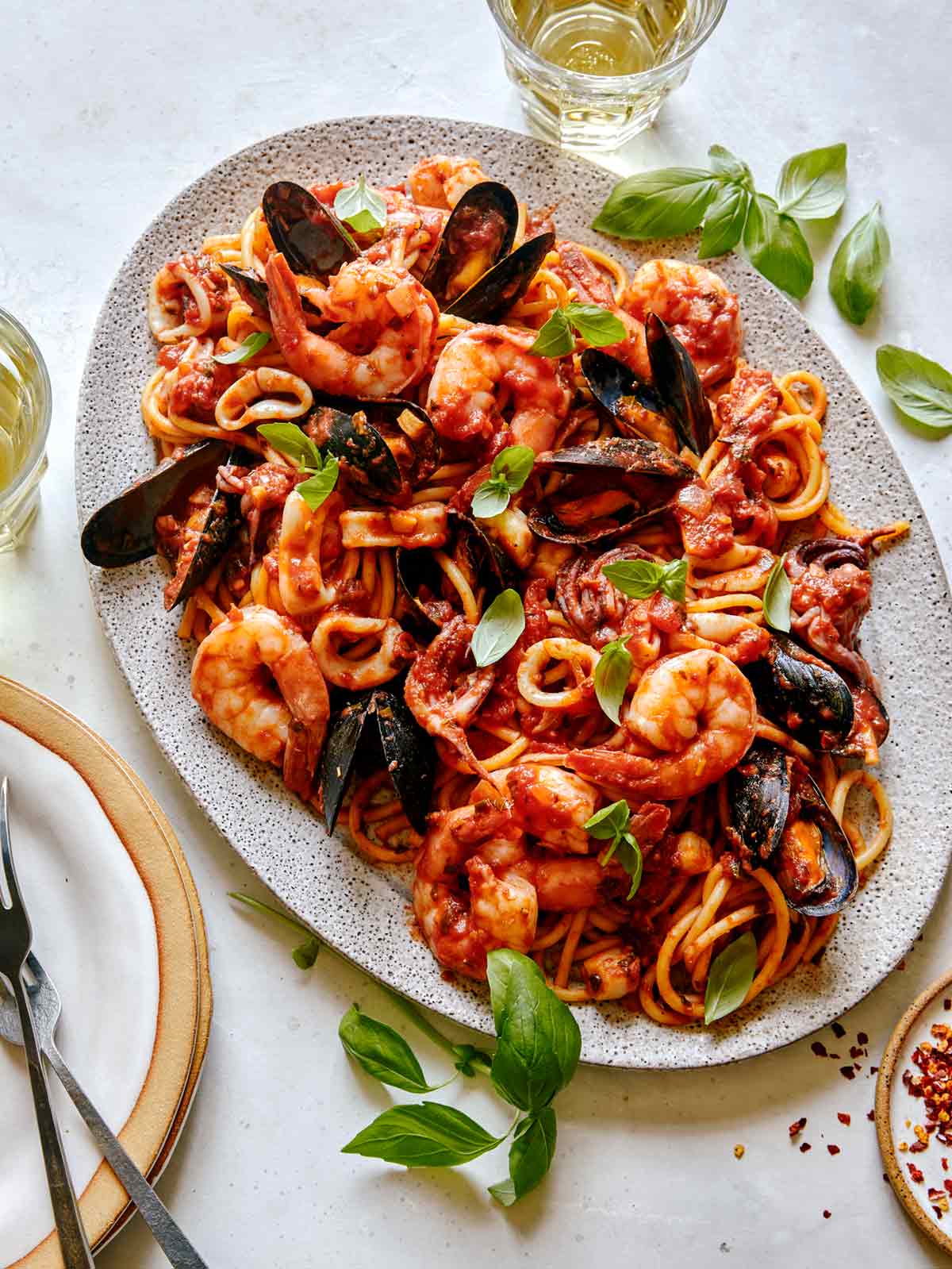 Frutti Di Mare recipe on a platter with basil leaves on the side.