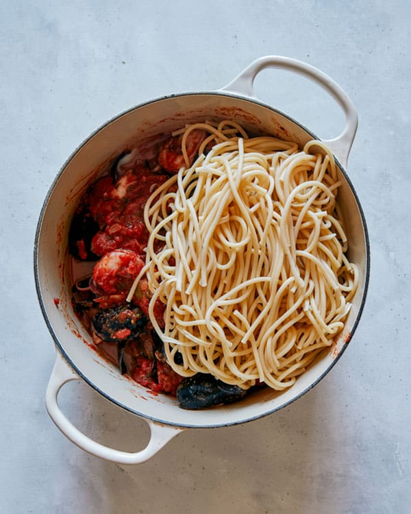 Frutti di mare with pasta being added to the pot.