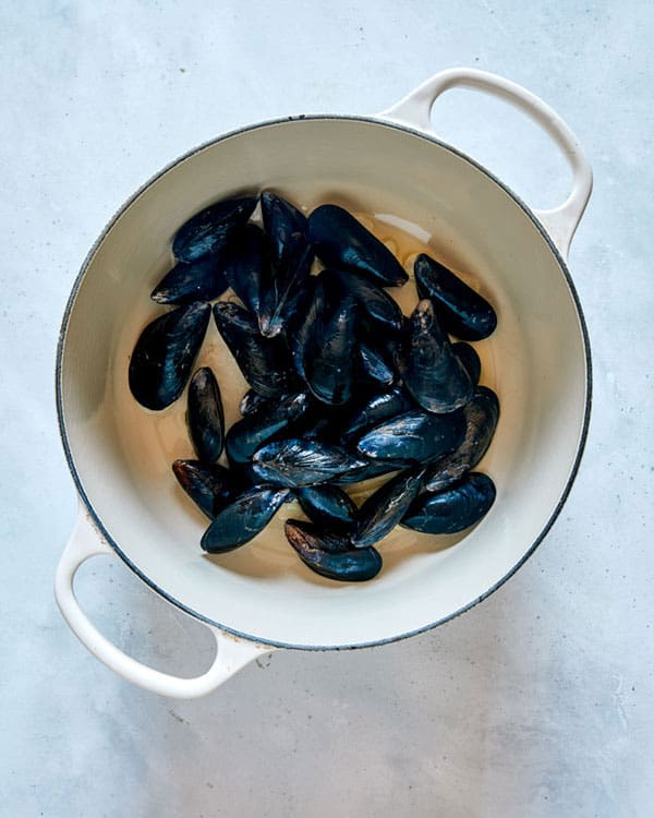 Mussels cooking in a pot with garlic and oil to make Frutti Di Mare.