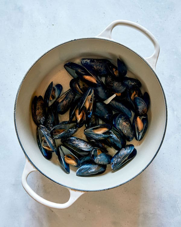 Cooked mussels in a pot with oil and garlic.