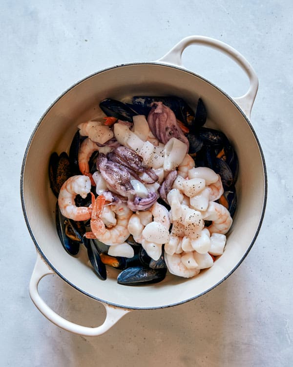 Seafood being cooked in a pot to make frutti di mare.