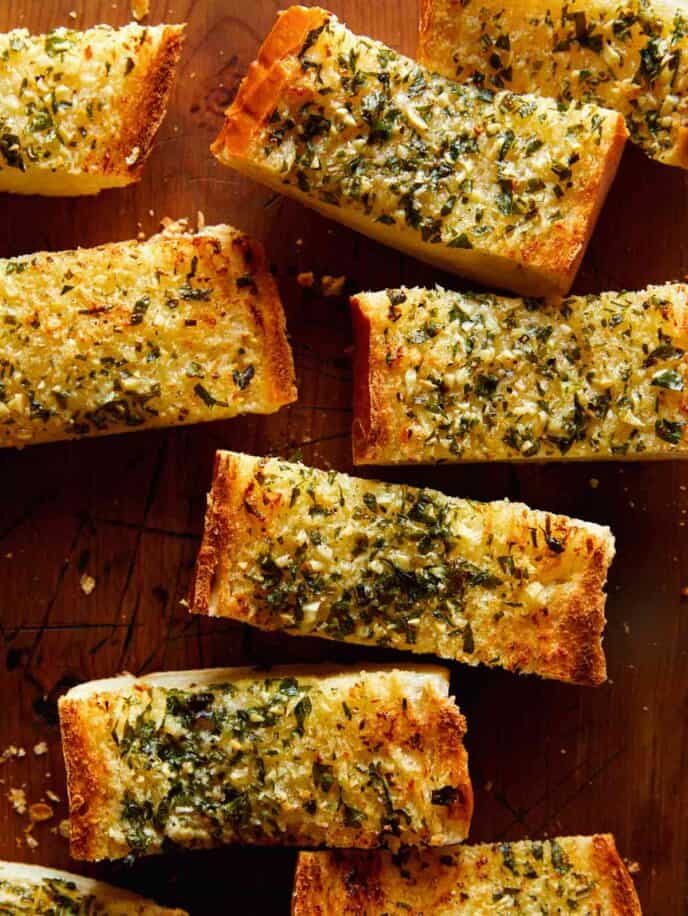 Close up on homemade garlic bread cut into slices on a cutting board.