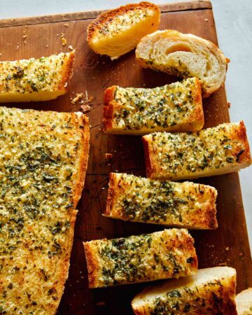 Homemade garlic bread recipe on a cutting board with some cut up.