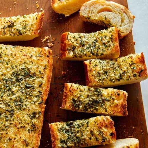 Homemade garlic bread recipe on a cutting board with some cut up.