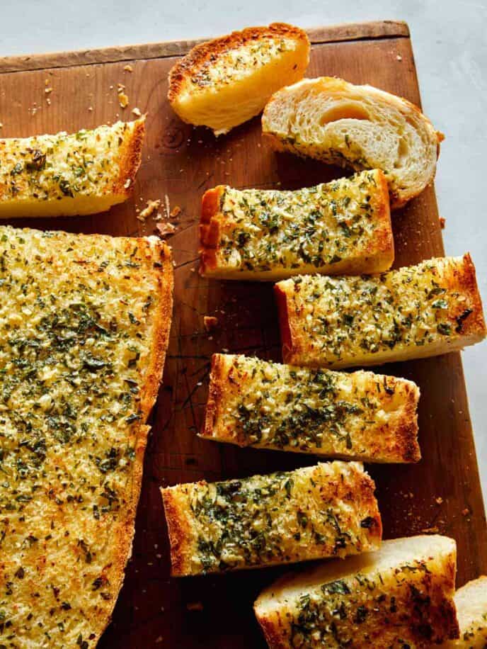 Homemade garlic bread recipe on a cutting board with some cut up. 