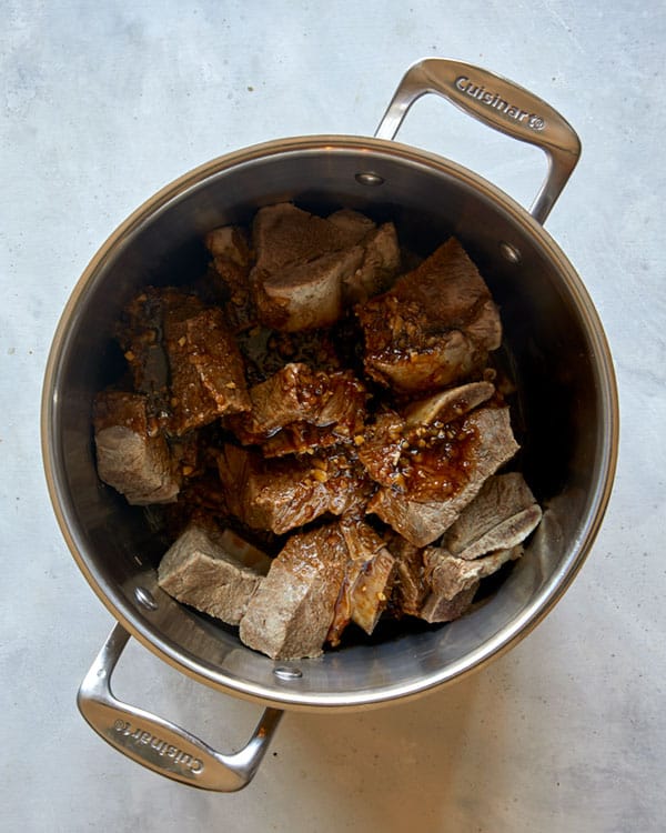 Short ribs in a pot with braising liquids.
