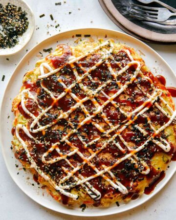 Okonomiyaki on a plate with fork next to it.