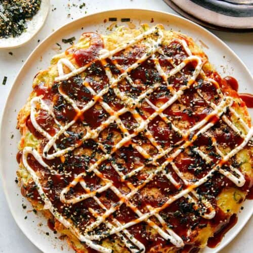 Okonomiyaki on a plate with fork next to it.