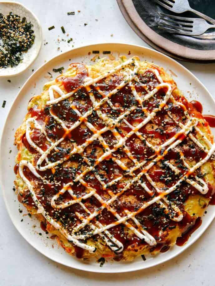 Okonomiyaki on a plate with fork next to it.