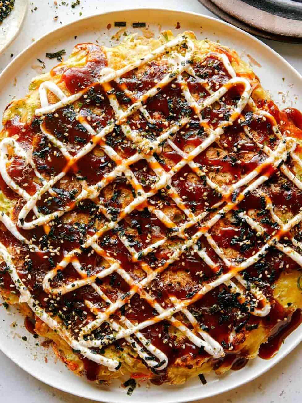 Okonomiyaki on a plate with fork next to it.